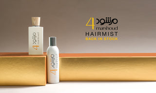 Two bottles of Atyab Al Marshoud 4 Hair Mist and Marshoud 4 white perfume displayed on a golden platform with Arabic and English branding, featuring the text 'Hairmist Back in Stock' on a beige background