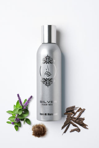 Silver hair mist bottle with herbs on a white background featuring its ingredients by Atyab Al Marshoud.