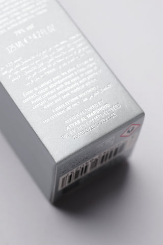 Close-up of a silver rectangular product packaging with text and a barcode on a light gray background by Atyab Al Marshoud.