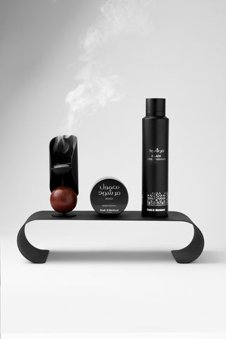 Set of Mamool products including a bottle of Home Fragrance, a Bakhoor, and a round container on a white stand with a light gray background by Atyab Al Marshoud.