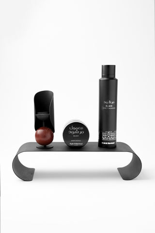 Set of hair care products on a black metal stand against a white background by Atyab Al Marshoud.