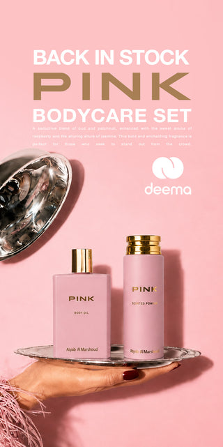Pink bodycare set by Deema on a pink background, featuring a pink bottle of body oil and a pink bottle of body butter on a silver tray, with a hand holding the tray. Text reads 'BACK IN STOCK PINK BODYCARE SET'.